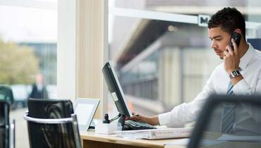 man on computer with phone